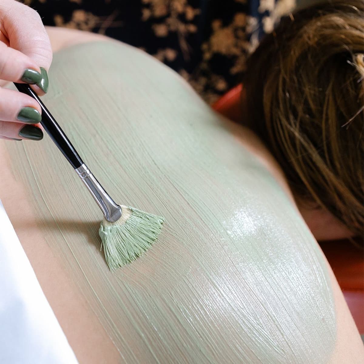 Applying a refreshing body mask during a spa treatment for skin rejuvenation and hydration.