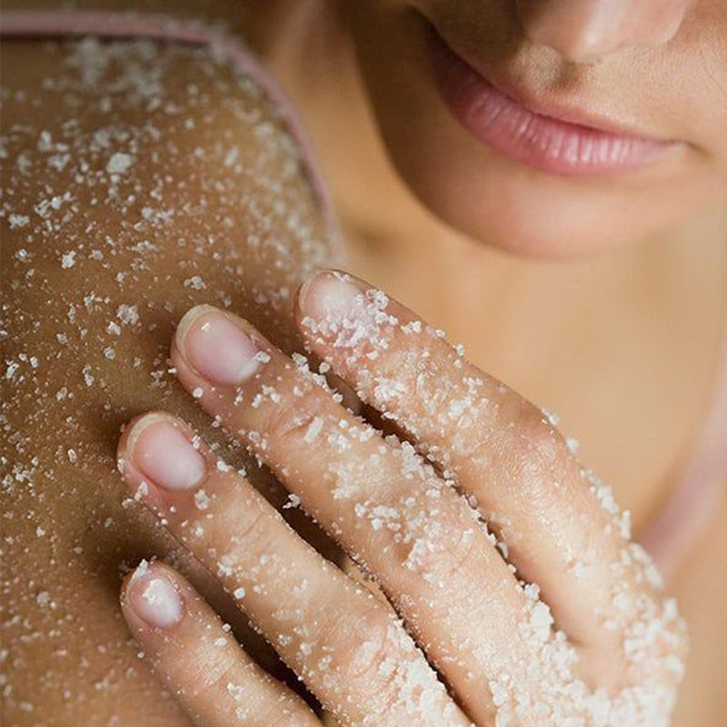 Close-up of a person applying Body Scrubs, showcasing smooth skin with exfoliating granules.