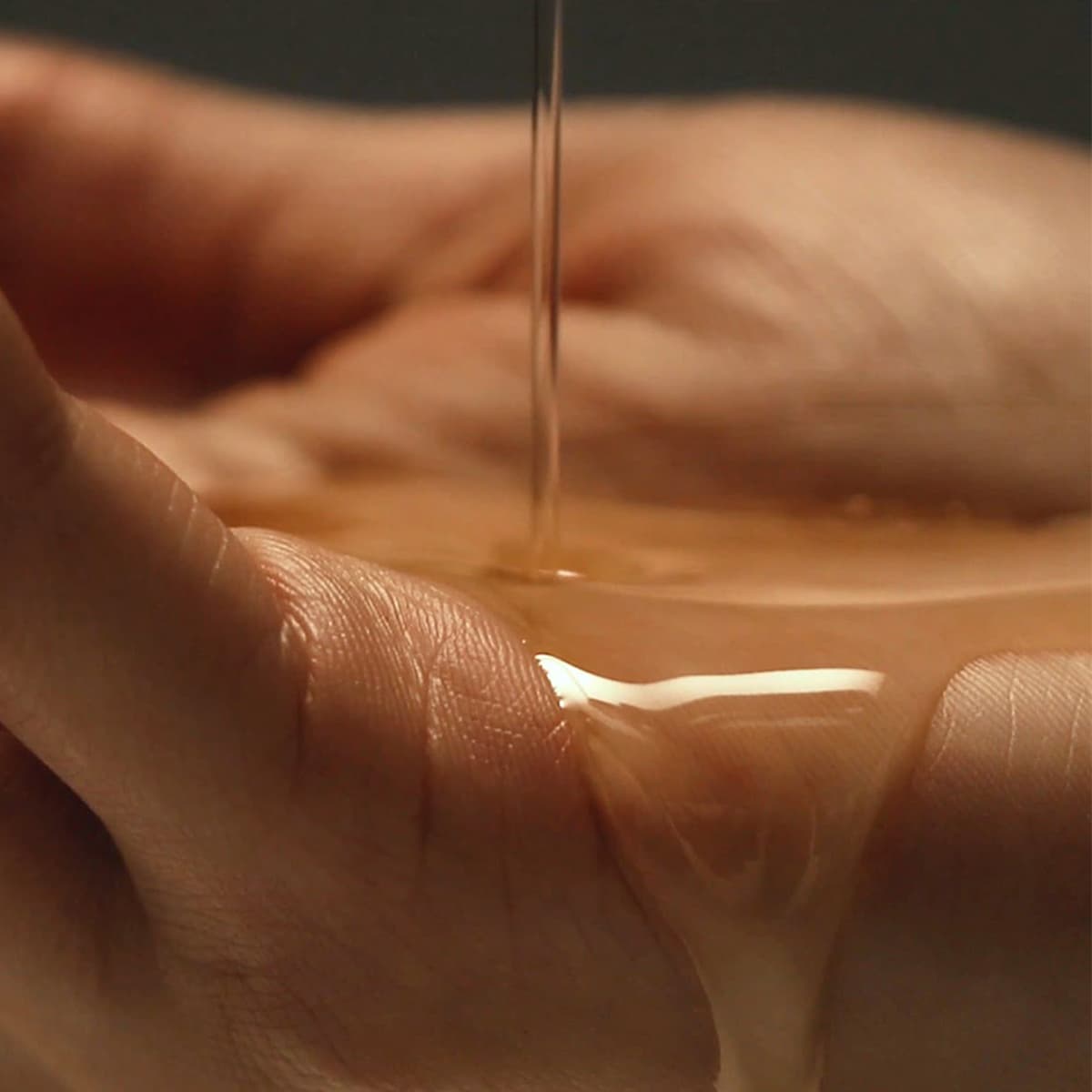 A hand catching golden massage oils, highlighting the smooth texture and nourishing properties of massage oils.