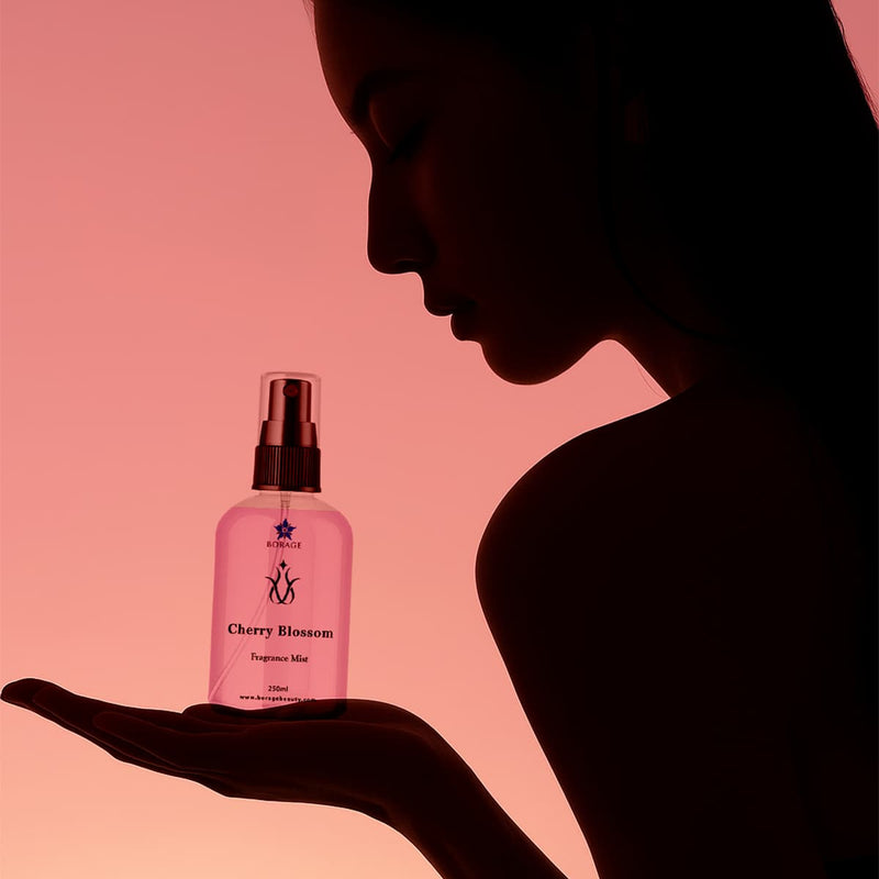 Silhouette of a woman holding a pink bottle of Cherry Blossom Spa Fragrances against a soft pink background.