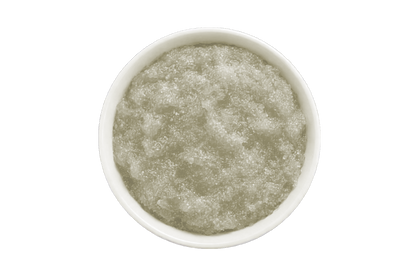 White bowl filled with a greenish-brown scrub on a white background