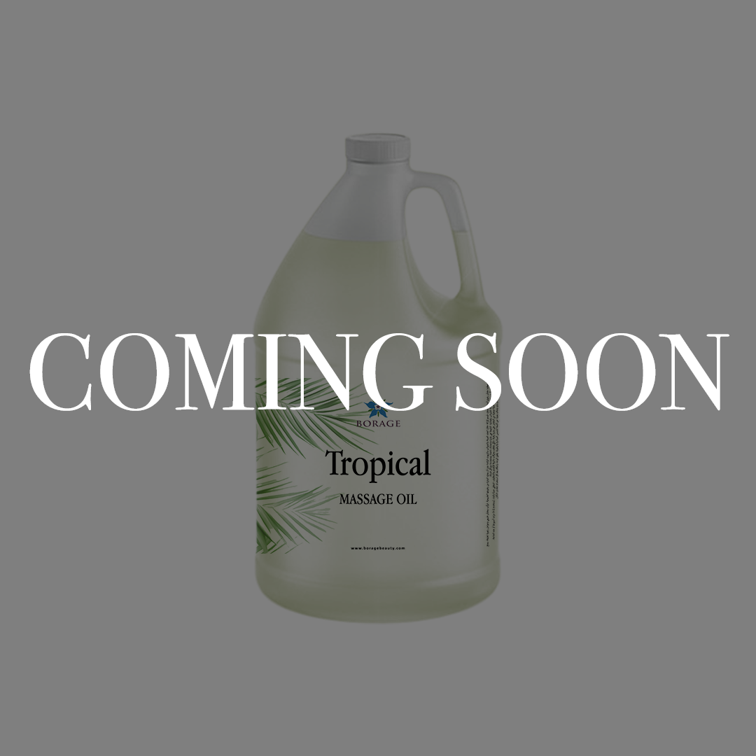 A large plastic jug of massage oil on a gray background with large white text reading 'COMING SOON' across the center. The label shows 'Tropical' and 'MASSAGE OIL' with a palm leaf graphic.