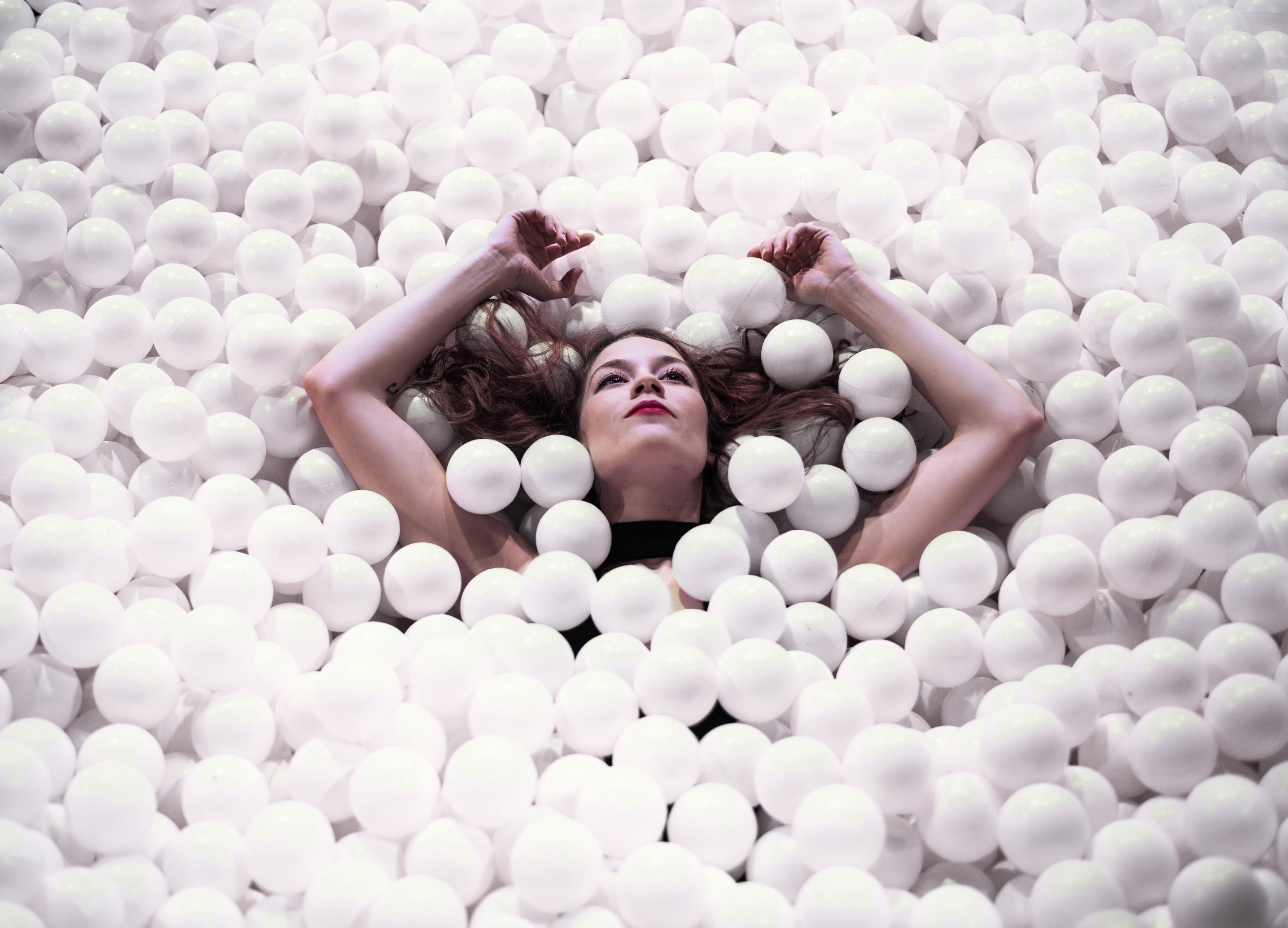 Woman lying on a bed of white balls